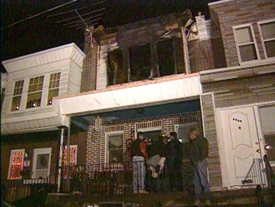 a group of people are standing outside of a brick house