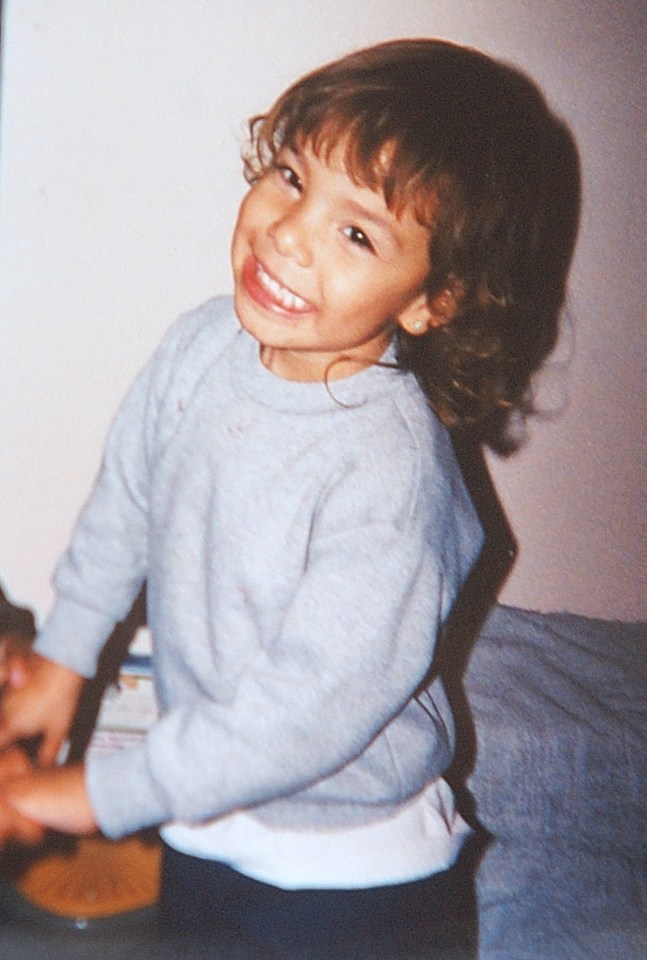 a young girl wearing a grey sweater smiles for the camera