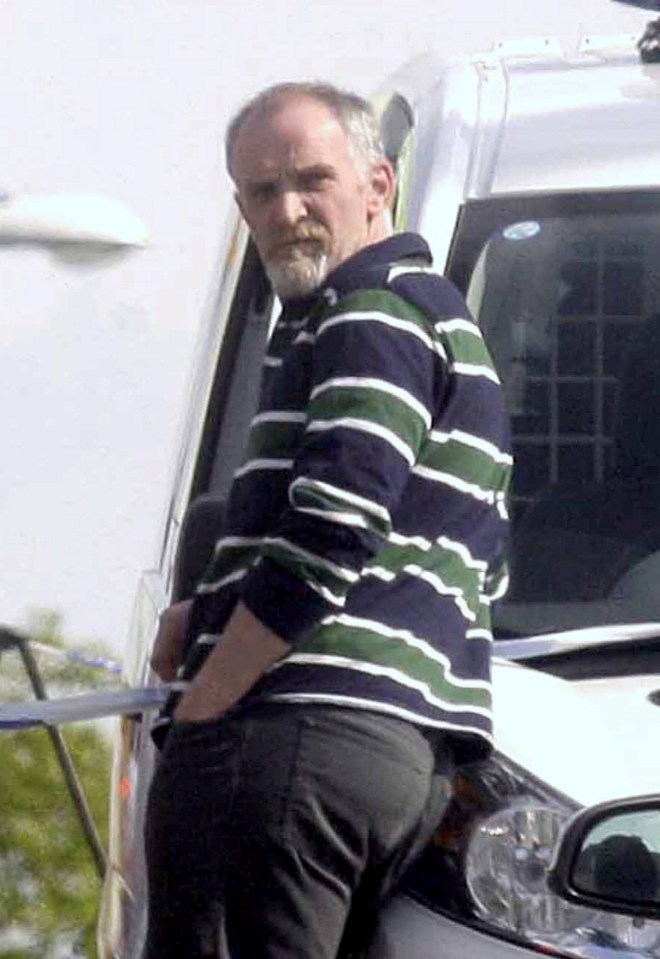 a man in a striped shirt is standing in front of a van