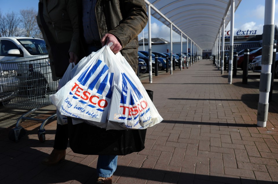 a person is carrying a bag of tesco bags