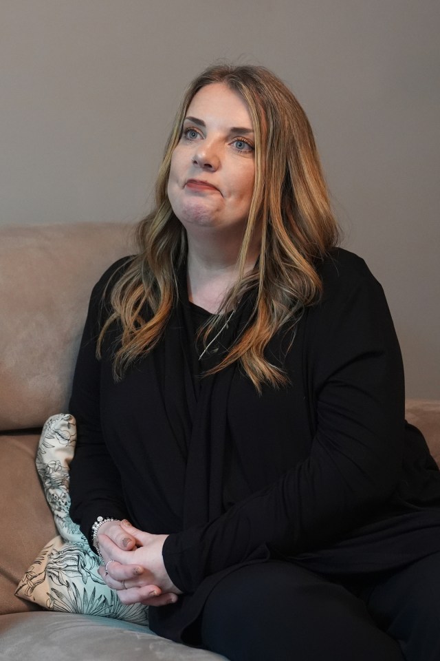 a woman sitting on a couch with her hands folded