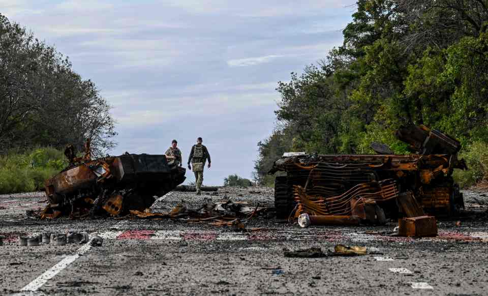 Ukrainian forces walk past a decimated vehicle in the Kharkiv region where fighting has been ongoing for months