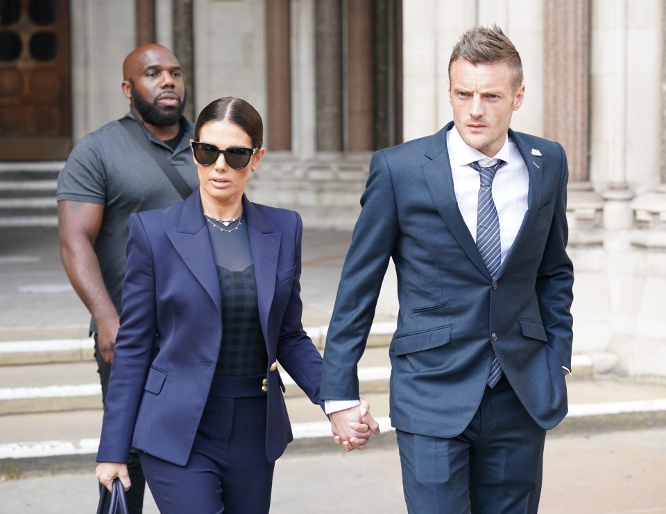 a man in a suit and tie holds hands with a woman in a suit