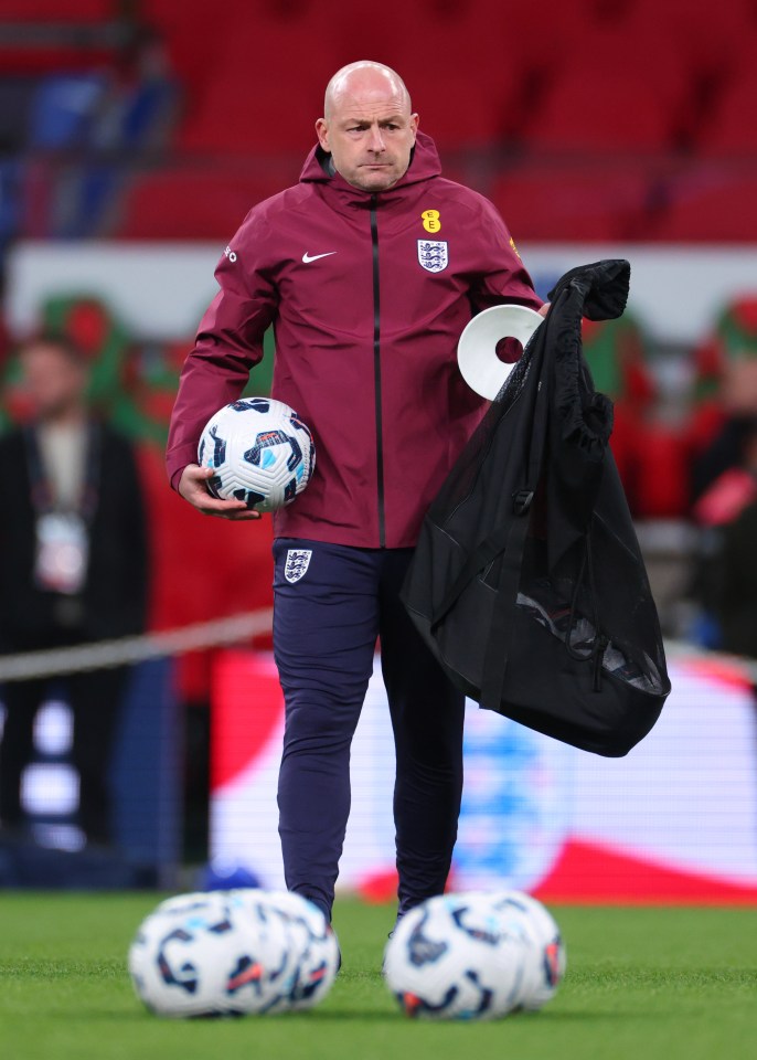 a man in a maroon nike jacket holds a soccer ball