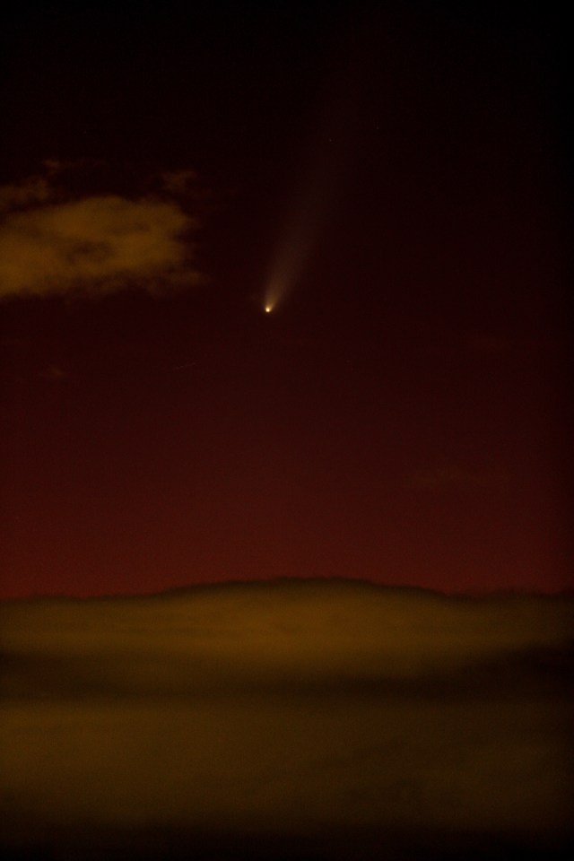 a comet is visible in the night sky above a desert