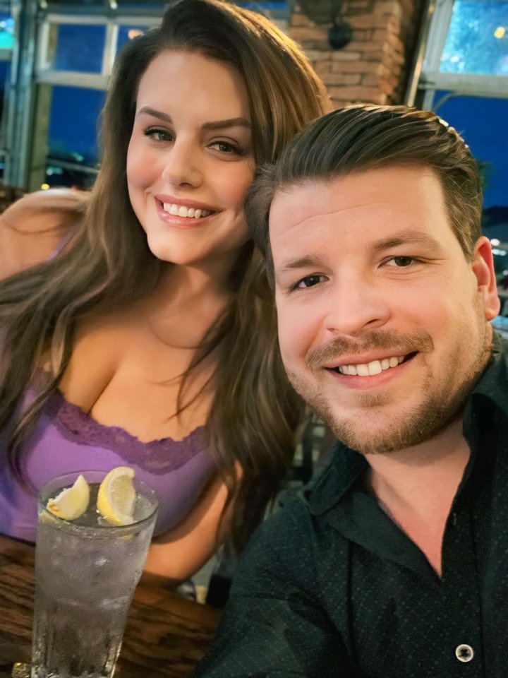 a man and a woman are posing for a picture with a glass of water with lemon slices in it