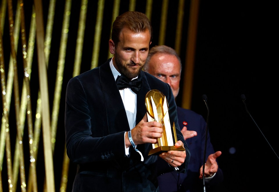 a man in a tuxedo is holding a trophy