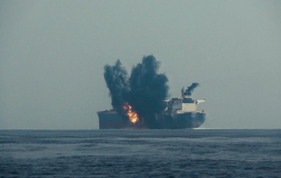 a large ship is exploding in the middle of the ocean