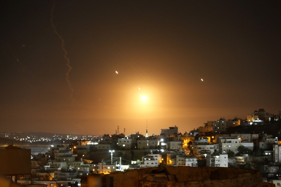 a rocket is flying over a city at night