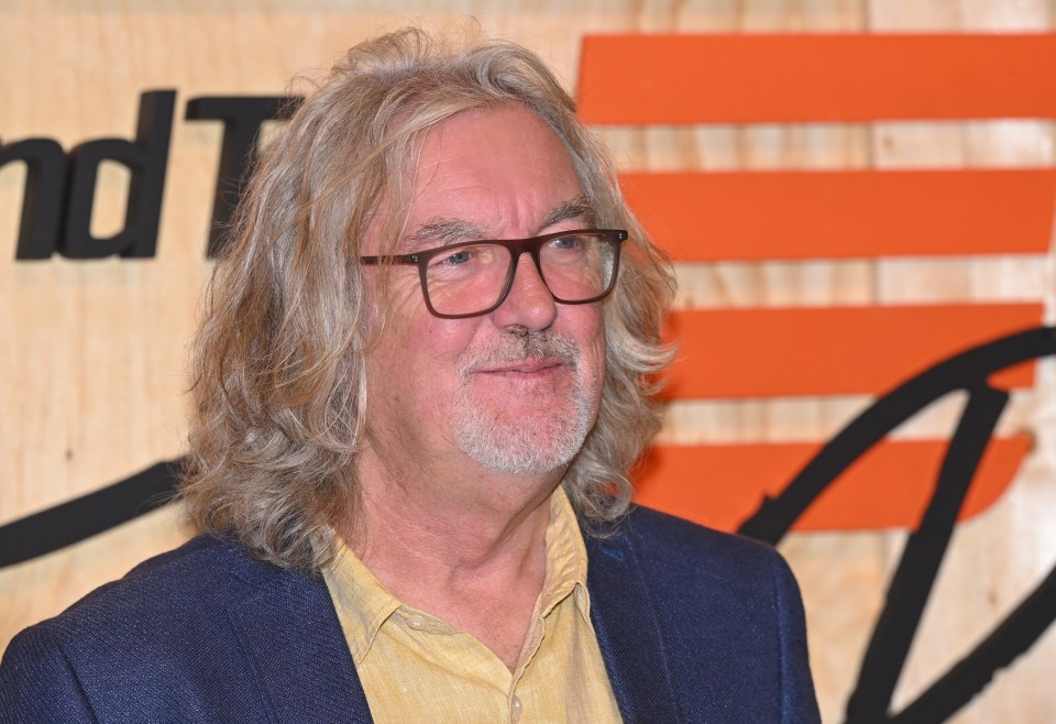 a man with long hair and glasses stands in front of a sign that says nd t