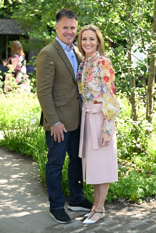 a man and woman pose for a picture in a garden