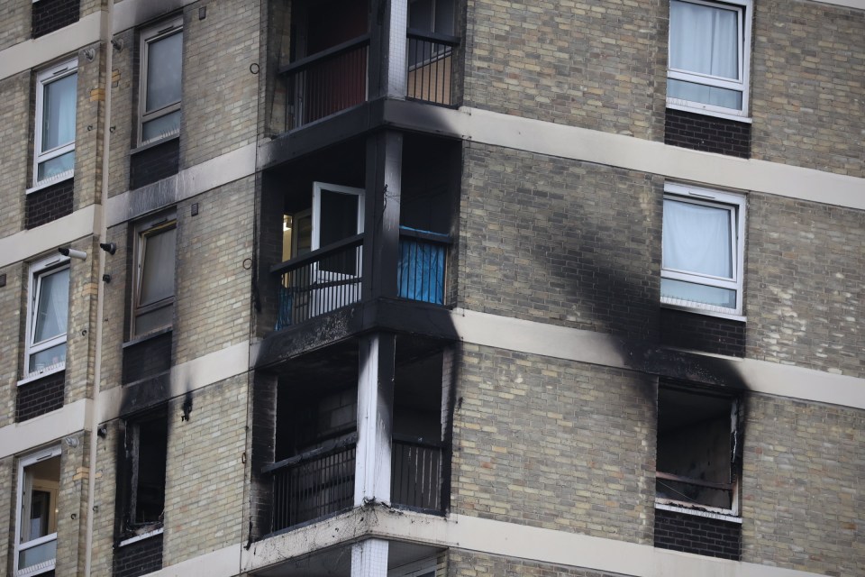 a brick building with a balcony that has smoke coming out of it