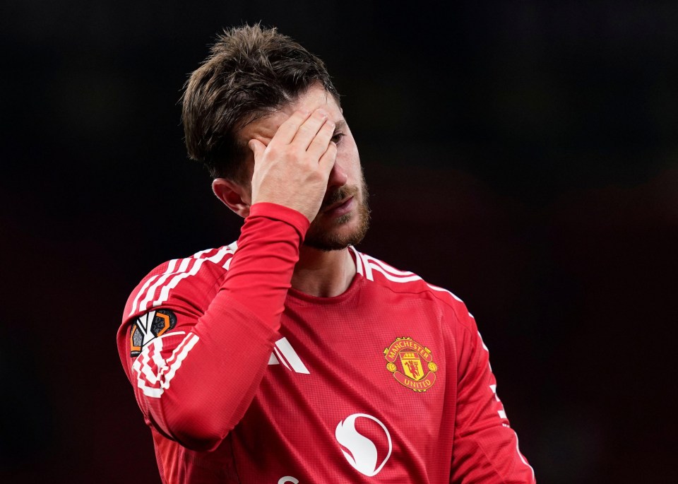 a man wearing a red manchester united jersey covers his face with his hand