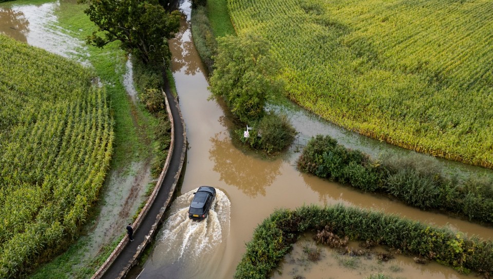 Cars drive through flooded roads near Kellaways in Wiltshire