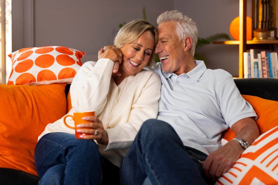 a man and a woman are sitting on a couch laughing