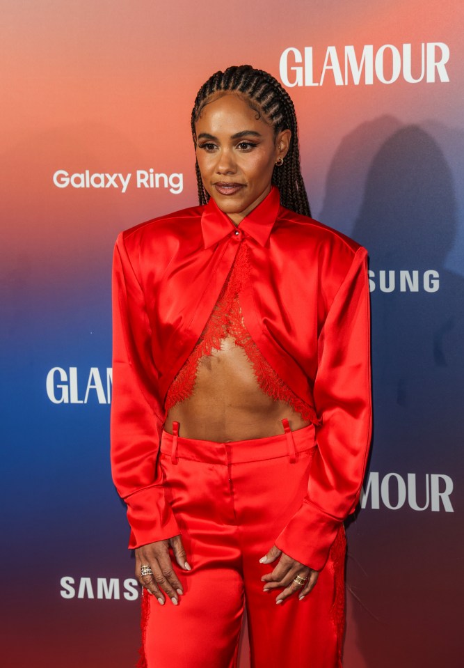 a woman in a red suit stands in front of a glamour sign