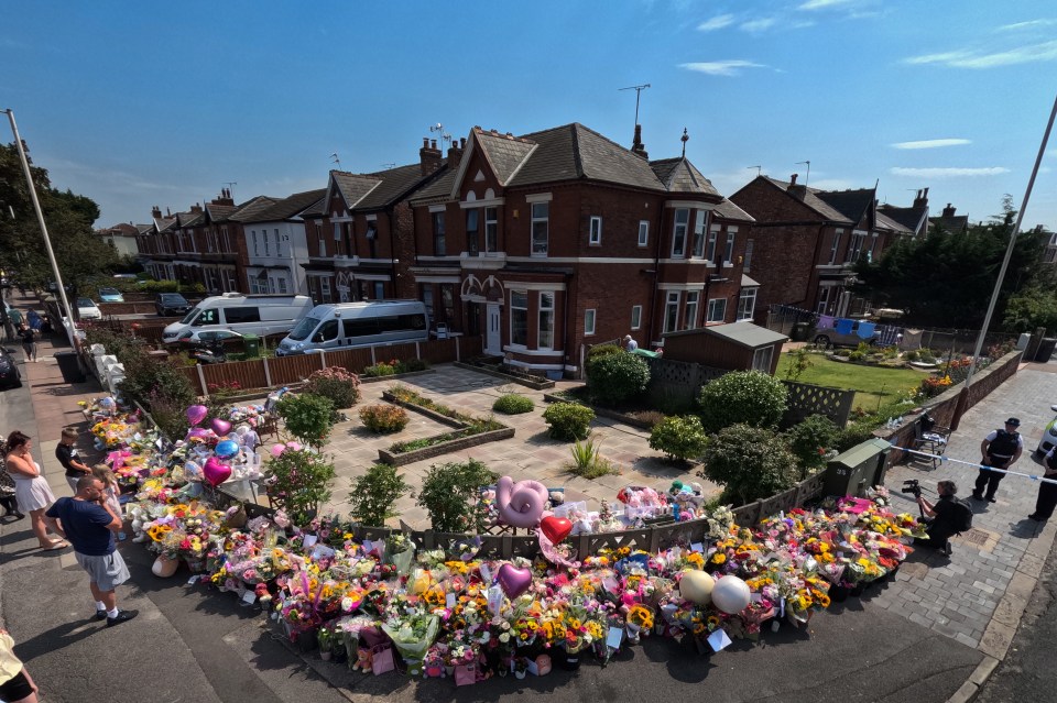 a bunch of flowers and balloons in front of a house