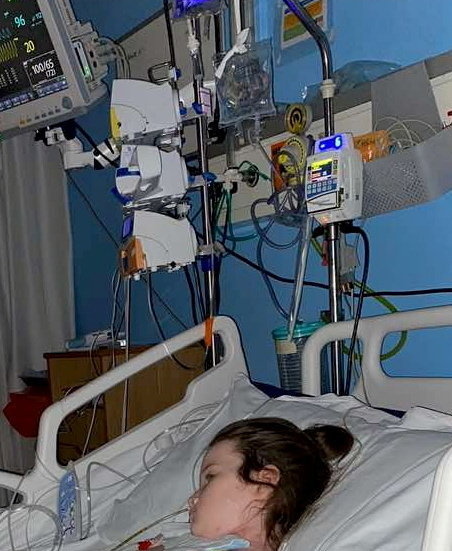 a young girl is laying in a hospital bed with a lot of medical equipment .