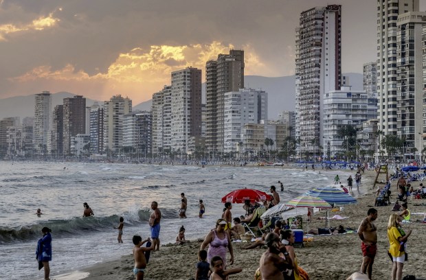 a beach scene with a coca cola umbrella in the foreground