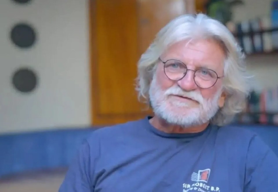 a man with glasses and a beard is sitting on a couch .