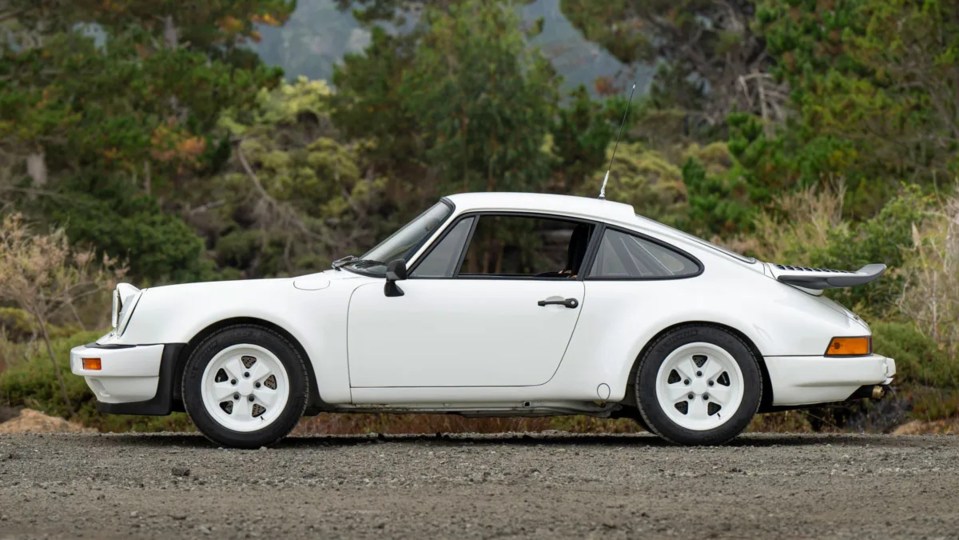 a white porsche is parked on a dirt road