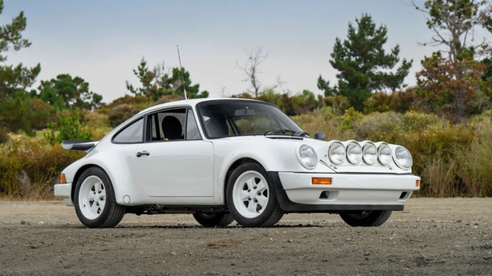 a white porsche is parked on a dirt road