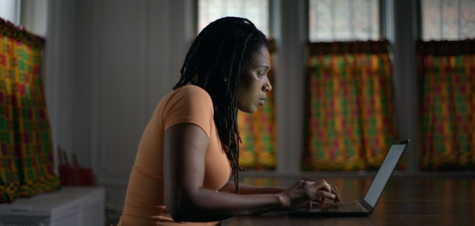 a woman with dreadlocks is typing on a laptop