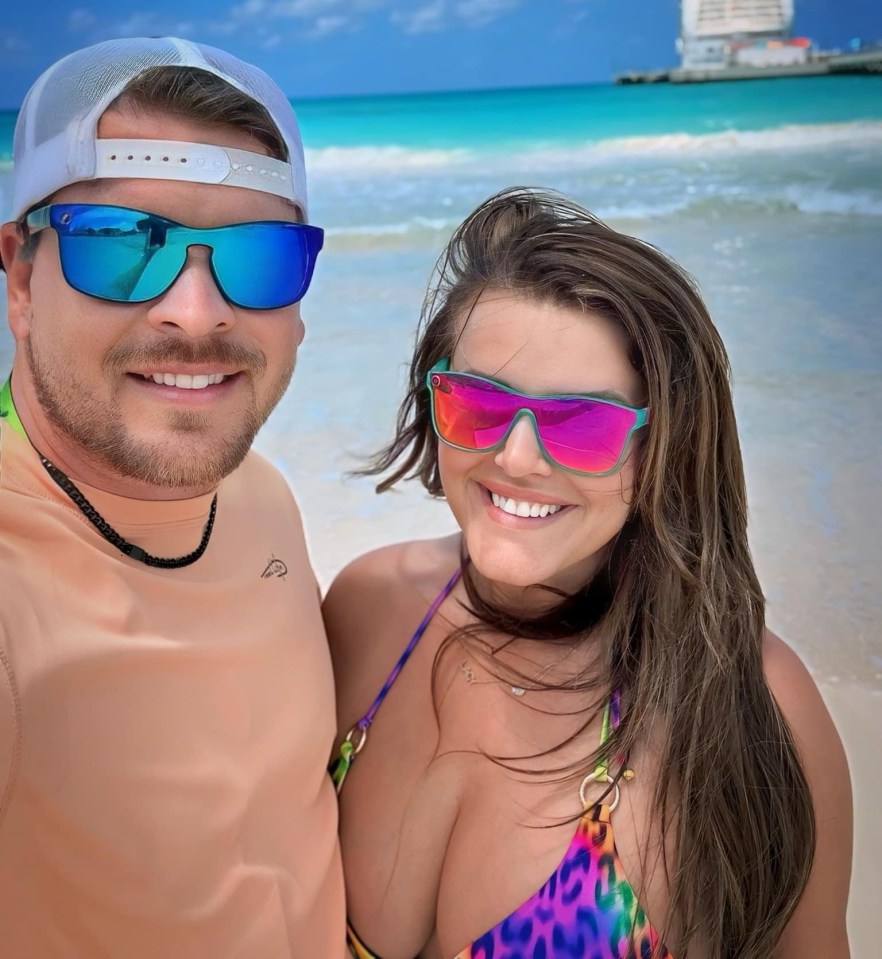 a man and a woman wearing sunglasses on a beach with a cruise ship in the background