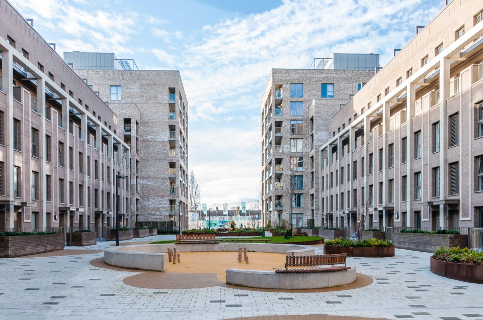 a row of brick buildings with a playground in the middle