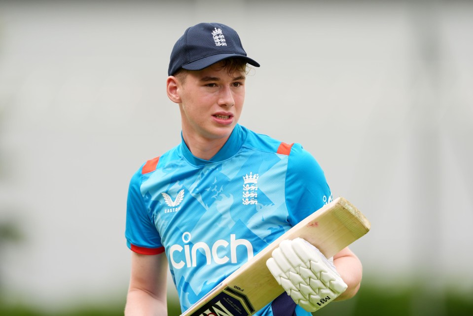 a young man wearing a cinch shirt holds a cricket bat