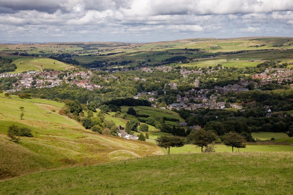 a small town sits in the middle of a lush green valley