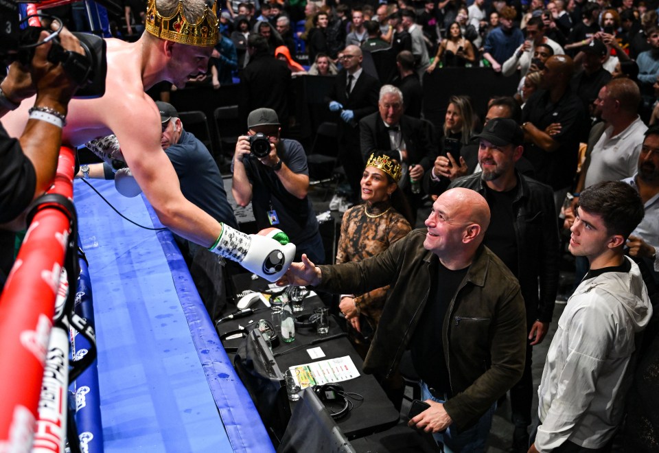 a man wearing a crown shakes hands with another man in a boxing ring