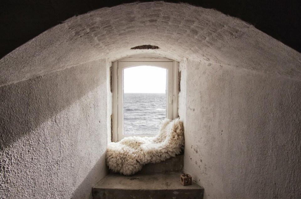 a window with a blanket on it looking out to the ocean