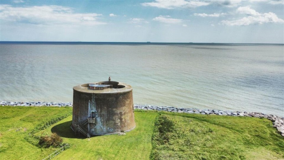 a tower on a grassy hill overlooking the ocean