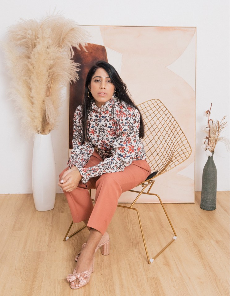 a woman sits in a chair in front of a painting