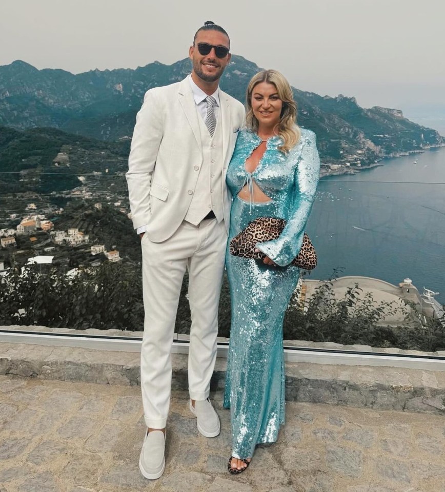 a man in a white suit stands next to a woman in a blue dress