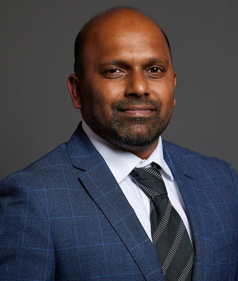 a man in a suit and tie smiles for the camera