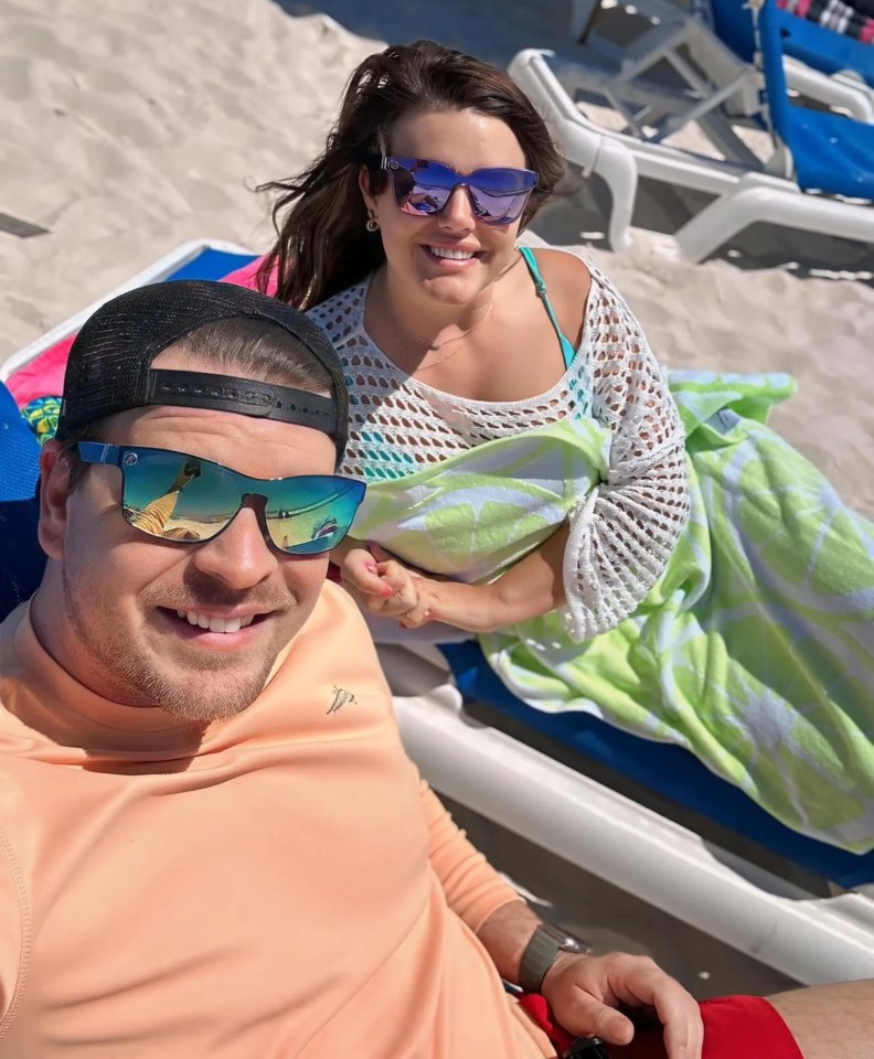 a man and a woman wearing sunglasses are sitting on a beach