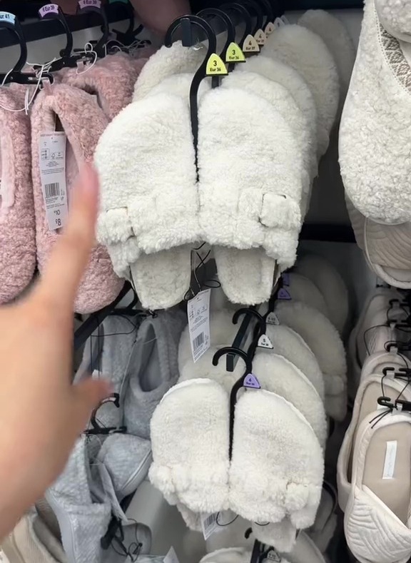 a person reaches for a pair of white slippers in a store