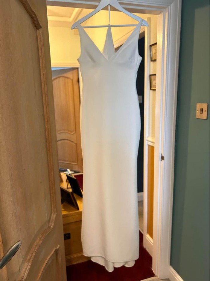 a white dress hangs on a white hanger in a doorway