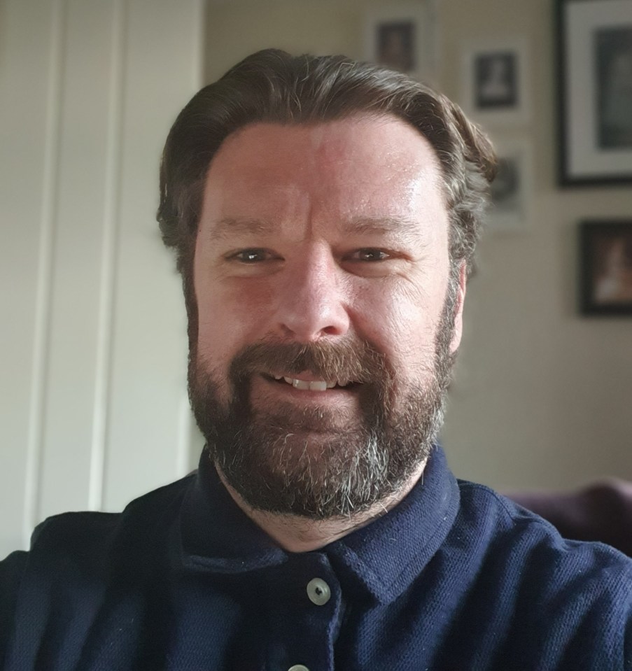 a man with a beard is smiling in front of a sign that says lego