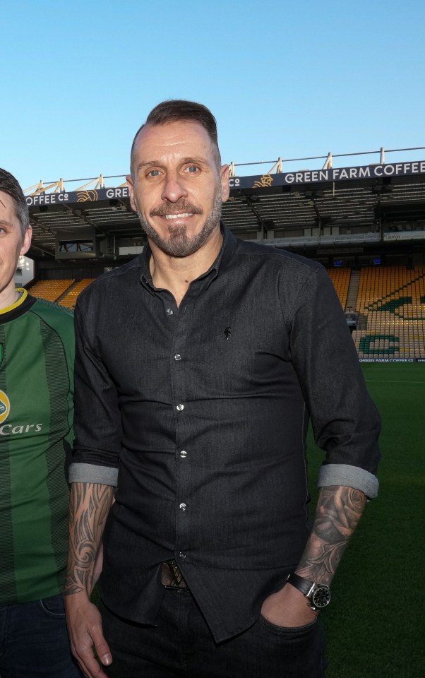 a man in a lotus cars shirt stands next to another man