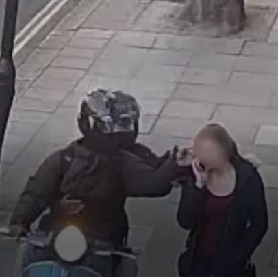 a man on a scooter is talking on a cell phone to a woman .