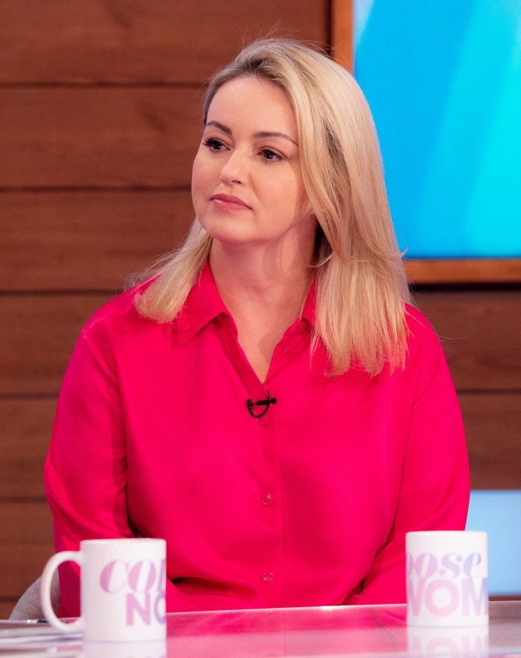 a woman in a pink shirt sits at a table with a cup that says rose nom