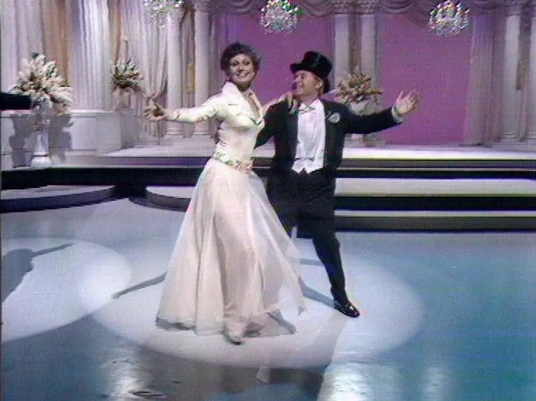 a man in a top hat is dancing with a woman in a white dress