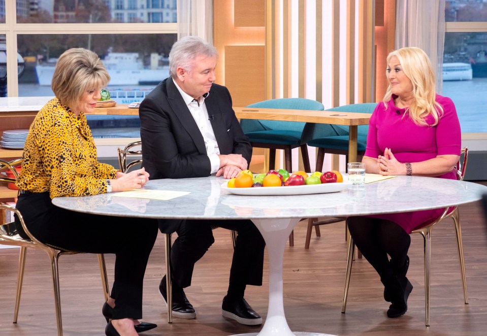 a woman in a pink dress sits at a table with two men