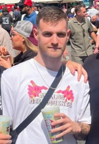 a man in a white t-shirt is holding a drink in his hand .