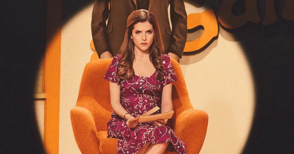 a woman in a purple dress sits in an orange chair