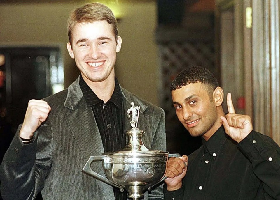 a man holding a trophy next to another man who is giving a thumbs up