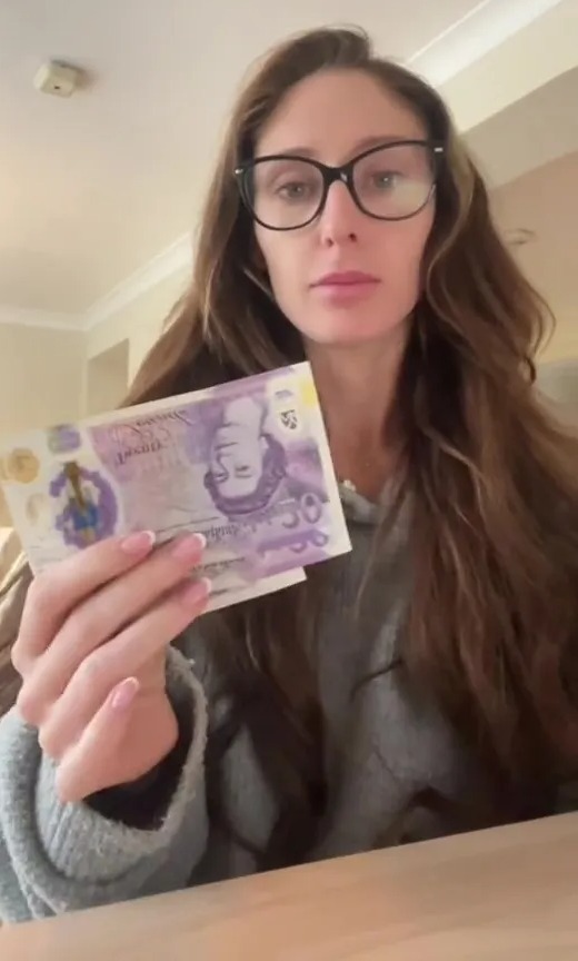 a woman wearing glasses is holding a 50 pound note